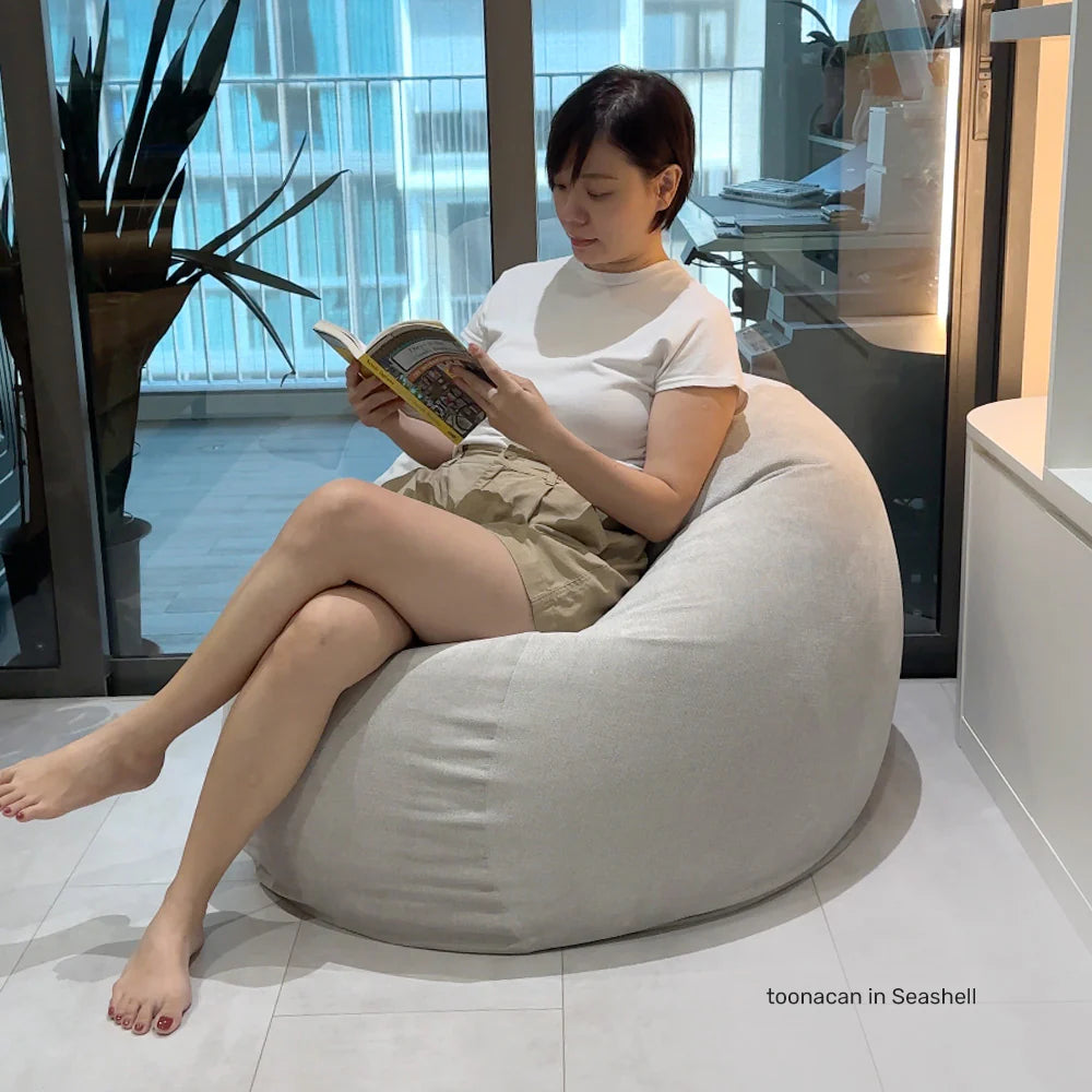 person reading a book, seated on a round fabric bean bag