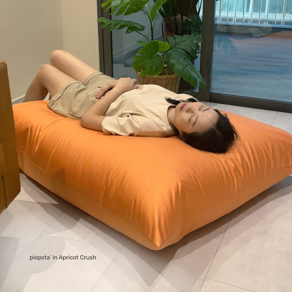 person lying down on a rectangle versatile bean bag in mattress position